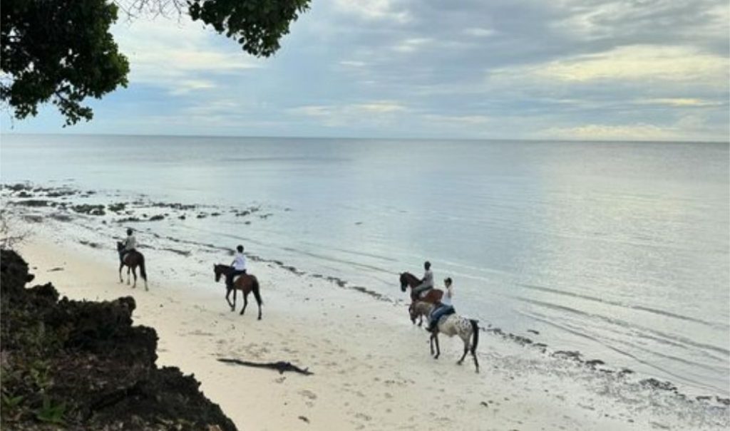 People riding horses on a sandy beach in Diani